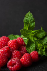 Raspberries with mint leaves on a black background.