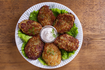 Potato pancakes with sour cream or yogurt. Vegetable fritters, latkes, draniki. View from above, top studio shot