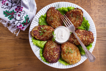 Potato pancakes with sour cream or yogurt. Vegetable fritters, latkes, draniki. View from above, top studio shot