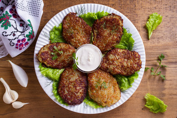 Potato pancakes with sour cream or yogurt. Vegetable fritters, latkes, draniki. View from above, top studio shot