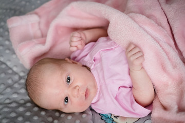 Baby girl looking into the camera in her bed