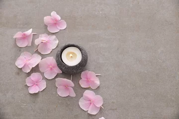  Many Pink hydrangea petals with candle in stone bowl on gray background © Mee Ting