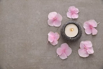 Deurstickers Many Pink hydrangea petals with candle in stone bowl on gray background © Mee Ting