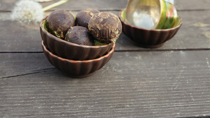 Vegan raw balls with nuts, date and carob . Fresh no-bake and no cooking dessert on wooden table with summer flowers.