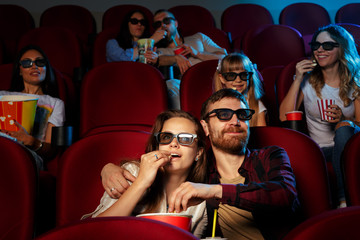Obraz premium friends sitting in cinema watch film eating popcorn and drinking water.