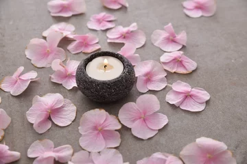 Fototapeten Viele rosa Hortensienblätter mit Kerze in Steinschale auf grauem Hintergrund © Mee Ting