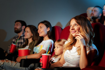 Group of friends sitting in movie theater with popcorn and drinks
