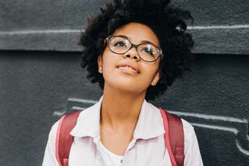 Attractive young african american student female wearing eyeglasses getting ready to go to college,...
