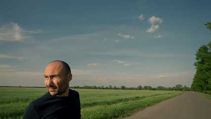 Naklejka na ściany i meble portrait of a farmer on the background of a field and a road.