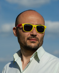 portrait of a businessman in modern sunglasses against a blue sky background.