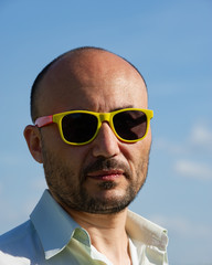 portrait of a businessman in modern sunglasses against a blue sky background.