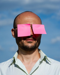 conceptual portrait of a businessman in modern sunglasses pasted with pink stickers against the...
