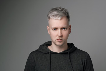 Young man with gray hair in casual clothes on white and gray background. Portrait in the studio. Creative hair coloring.