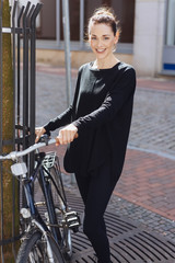 Fototapeta na wymiar lächelnde, elegante frau mit ihrem fahrrad in der stadt