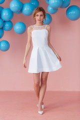 Full length portrait of smiling emotional young teen girl posing on pink wall backround decorated with blue balls