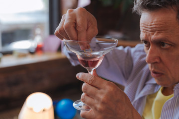 Goodbye wife. Close up of attractive male hands holding glass with alcohol and putting ring in it