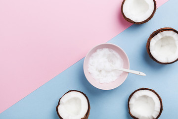 Coconut oil with fresh coconuts fruit on minimal pastel background top view. Natural and organic beauty cosmetic. Flat lay.