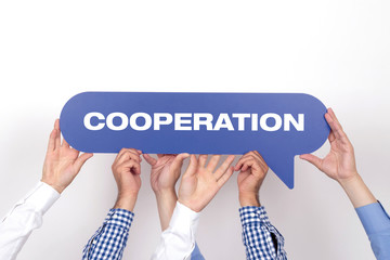 Group of people holding the COOPERATION written speech bubble
