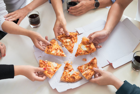 Image of teenage friends hands taking slices of pizza