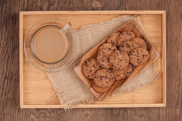 Delicious chocolate chip cookies on a tray on dark old wooden table