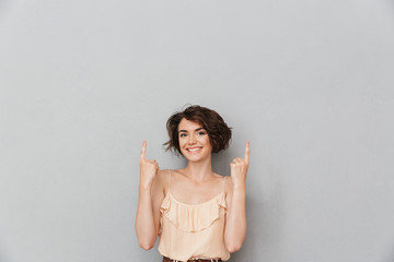 Portrait of a smiling young woman pointing fingers up