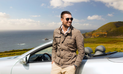 road trip, travel and people concept - happy man near convertible car over big sur coast of...