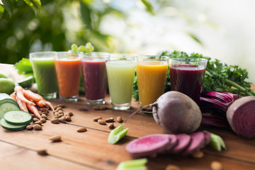 healthy eating, drinks, diet and detox concept - glasses with different fruit or vegetable juices and food on table over green natural background
