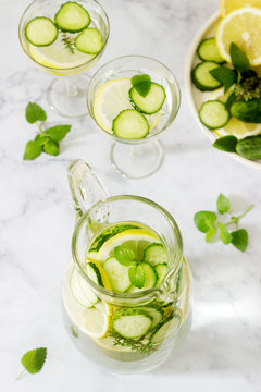 Lemonade with cucumber, lemon balm and thyme in a transparent jar on the background of plates with ingredients.