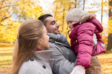 family, season and people concept - happy mother, father and little daughter at autumn park