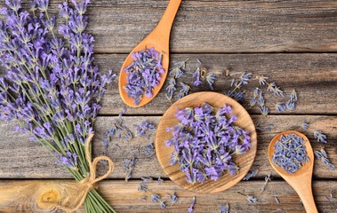 Top view of a bowl and wooden spoons with dried and fresh lavender flowers and a bouquet of...