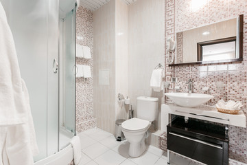 Bathroom Inside rooms of a apartment or hotel. Clean white towel and bathrobe on a hanger prepared to use.