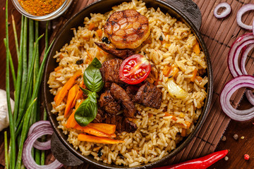 Homemade Uzbek pilaf from lamb served in cast iron cookware.