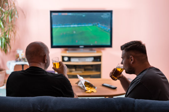 Father and son watching football or soccer on a TV.