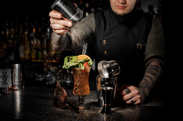 Professional bartender adding powder to a fresh summer cocktail with fruits