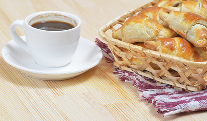 Hot homemade croissants in wicker basket on a wooden table