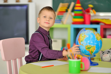A boy in the children's room playing at the table with the globe