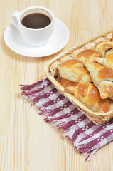 Small homemade croissants lie in a wicker basket