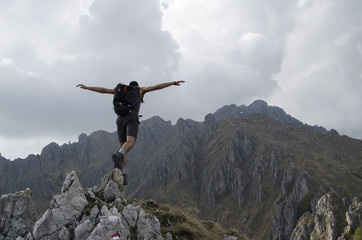 Hiker jumping down from the top of the mountain