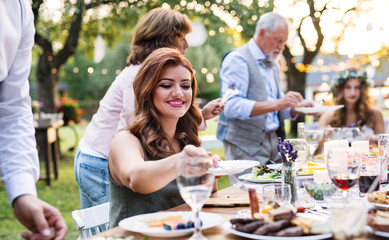 Guests eating at the wedding reception outside in the backyard.