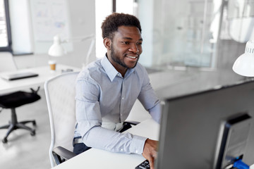business, people and technology concept - african american businessman with computer working at office