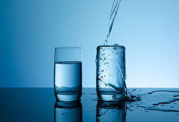 Creative splashing water in the glass on blue background