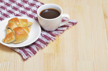 Croissants on a white plate, a cup of coffee