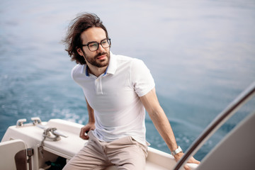Portrait of adult caucasian bearded tourist taking not far-avay sea journey on luxury white yacht...