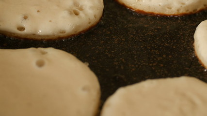 Closeup view fresh white pancake dough mixture frying in bubble vegetable oil on preheat cast iron pan at home