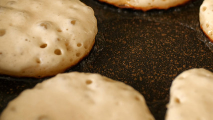 Closeup view fresh white pancake dough mixture frying in bubble vegetable oil on preheat cast iron pan at home
