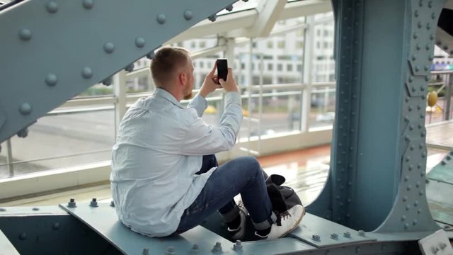 man is taking pictures on the phone while sitting on an iron construction