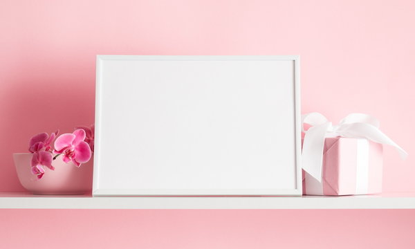 Photo frame mock up, beautiful flowers bouquet on the shelf, gift with white satin bow, pink orchid on pink wall background. 