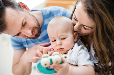 Young family and a baby boy with a toy at home. Close up.