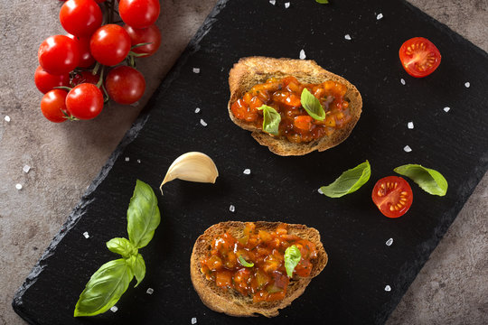 Homemade crispy Italian antipasto called Bruschetta topped with tomatoes, garlic, red pepper and basil