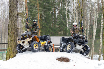 Two ATV riders with paintball guns sitting on quad bikes